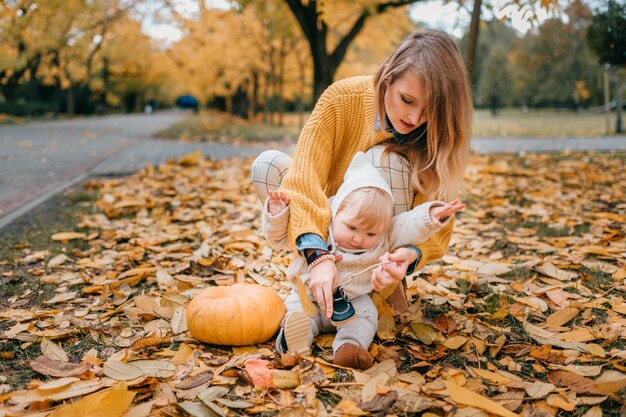 Joven madre bonita disfruta de pasar tiempo en el parque de otoño con su hijo pequeño