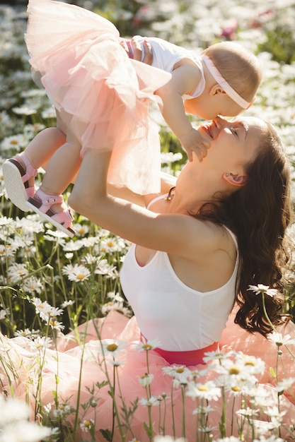 Joven madre bonita con su pequeño bebé al aire libre. Hermosa mujer con su hija en la naturaleza. niño pequeño con su padre en el campo de manzanilla