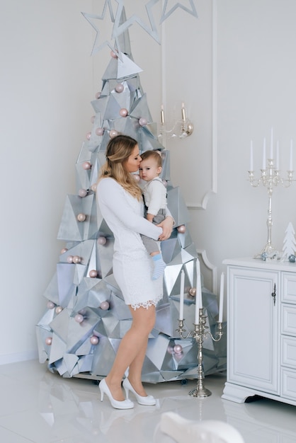 Joven madre caucásica con hijo pequeño cerca del árbol de Navidad