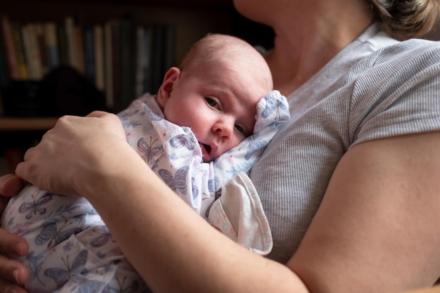 Joven madre caucásica sosteniendo a su bebé recién nacido pasando tiempo juntos