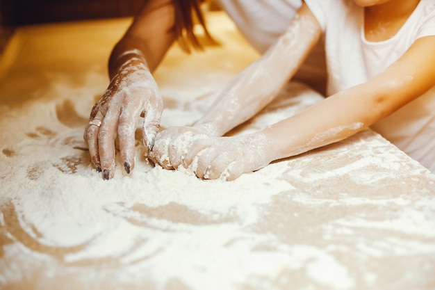 una joven madre se para en la cocina y trabaja con harina junto con su hijo