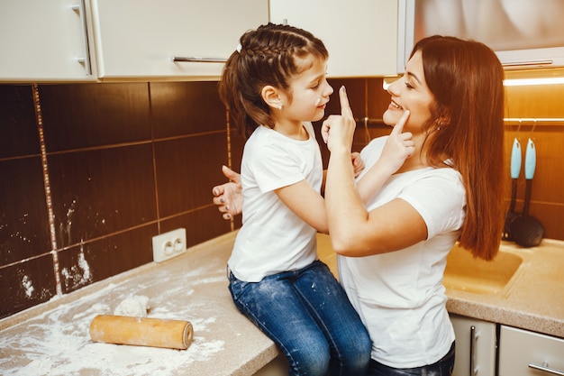 una joven madre se para en la cocina y trabaja con harina junto con su hijo