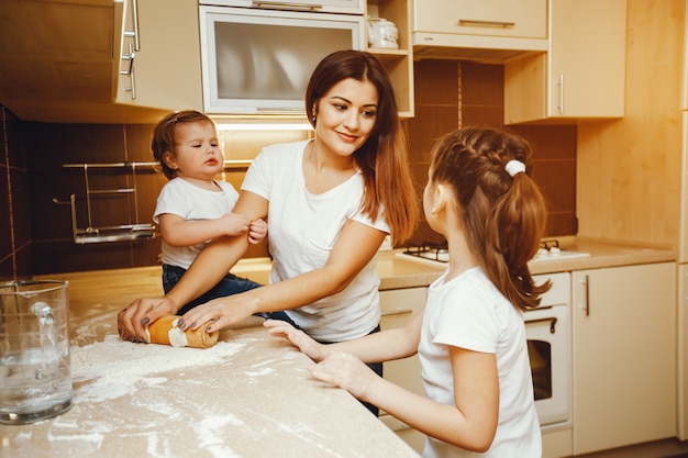 una joven madre se para en la cocina y trabaja con harina junto con sus hijos