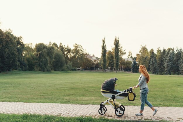 joven madre disfrutando de un paseo en el parque con el bebé