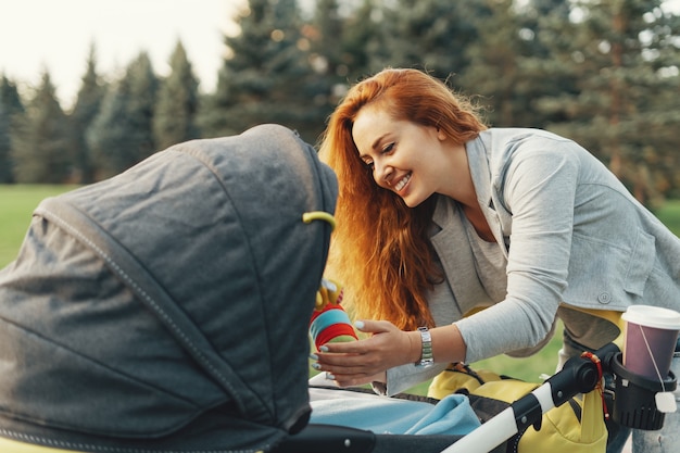 joven madre disfrutando de un paseo en el parque con el bebé