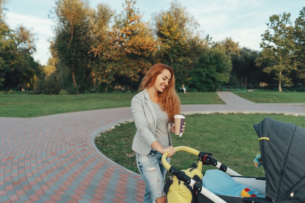 joven madre disfrutando de un paseo en el parque con el bebé