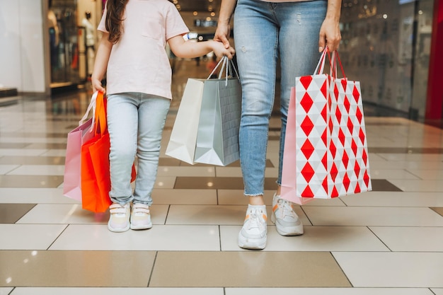 Joven madre e hija sosteniendo bolsas de compras en el centro comercial Compras familiares