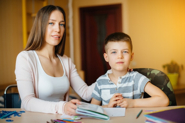 Una joven madre está haciendo los deberes con su hijo en casa