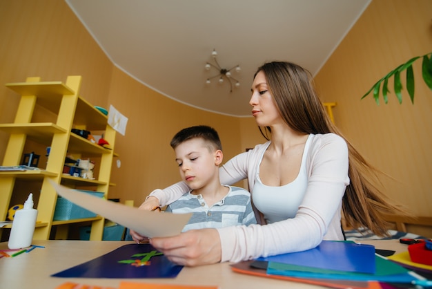 Una joven madre está haciendo la tarea con su hijo en casa. Padres y entrenamiento