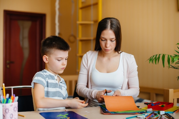 Una joven madre está haciendo la tarea con su hijo en casa. Padres y entrenamiento