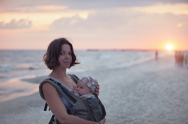 Una joven madre está en la playa con su bebé en una honda