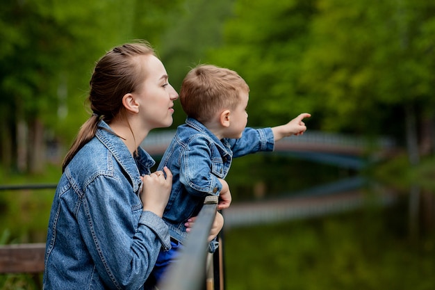 Joven madre feliz jugando y divirtiéndose con su pequeño hijo bebé en primavera cálida o día de verano en el parque. Concepto de familia feliz, día de la madre