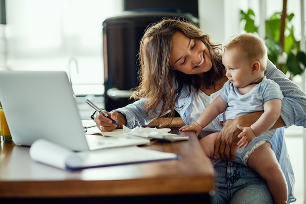 Foto joven madre feliz revisando las finanzas del hogar y comunicándose con su hijo