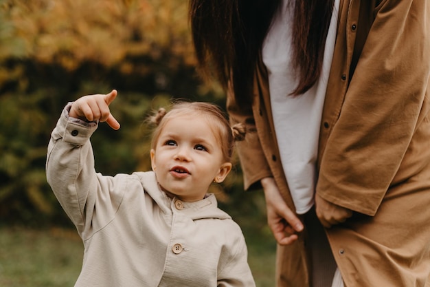 Joven madre feliz y sonriente con su pequeña hija en brazos abrazándose y besándose pasando un fin de semana en un paseo en el parque de otoño efecto de ruido de enfoque selectivo Estado de ánimo otoñal