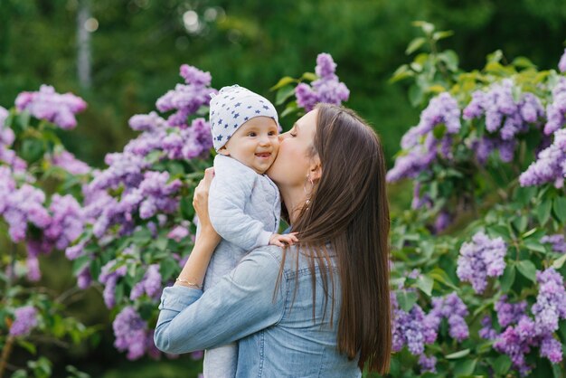 Una joven madre feliz sostiene a un lindo hijo en sus brazos una familia feliz jugando y acurrucándose en el parque