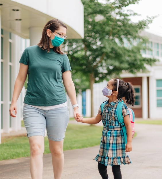 Foto una joven madre de la generación del milenio envía a su hija de vuelta a la escuela.