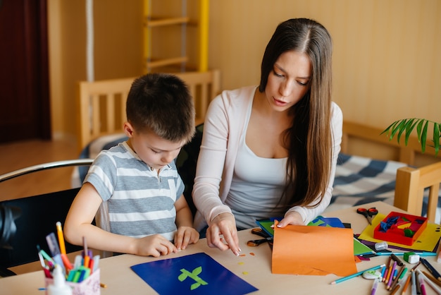 Foto joven madre está haciendo la tarea con su hijo en casa. padres y entrenamiento