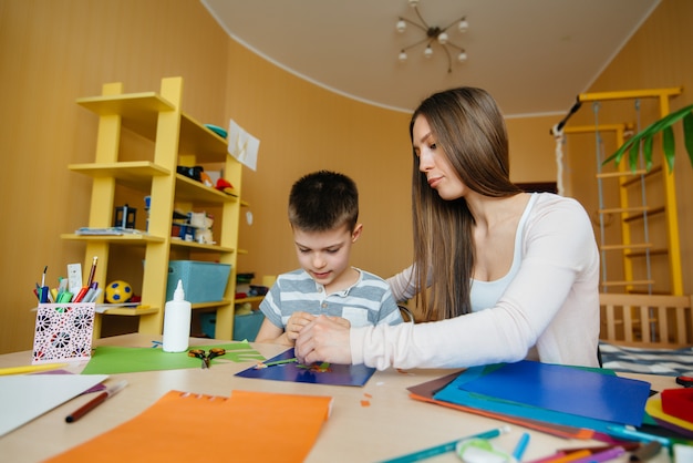 Foto una joven madre está haciendo la tarea con su hijo en casa. padres y entrenamiento