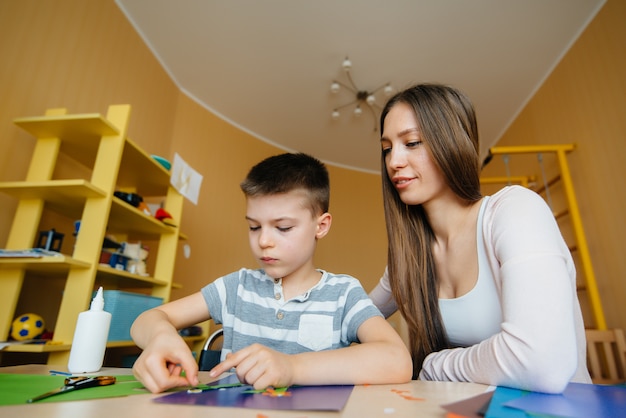 Foto una joven madre está haciendo la tarea con su hijo en casa. padres y entrenamiento