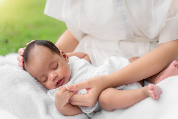 Joven madre hermosa asiática sosteniendo a su recién nacido está durmiendo