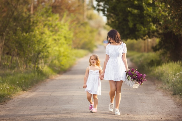 Joven madre hermosa y pequeña hija divirtiéndose juntos. Linda mamá y linda chica al aire libre. Alegre familia juntos rinning tomando de la mano