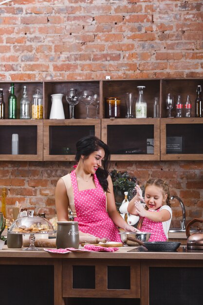 Joven madre hermosa y su pequeña hija cocinando juntos en la cocina