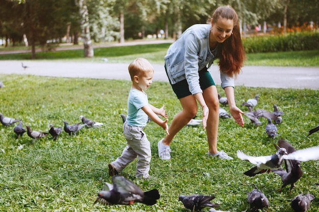 Joven madre con un hijo pequeño divirtiéndose jugando en el parque