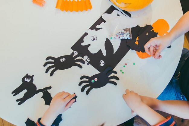 Joven madre con un hijo pequeño haciendo arañas artesanales para las vacaciones de halloween