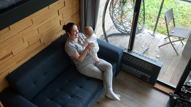 La joven madre juega con el bebé felizmente levantando al niño pequeño