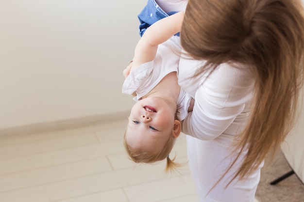 Joven madre jugando con su bebé en casa. Concepto de maternidad, lactancia y niños.