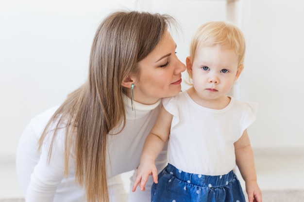 Joven madre jugando con su bebé en casa. Concepto de maternidad, lactancia y niños.