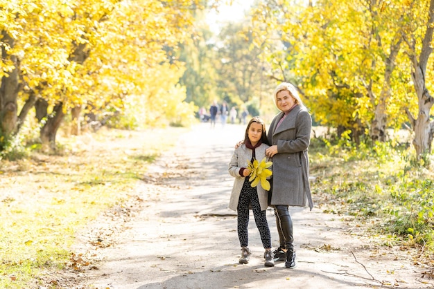 Joven madre jugando con su hija en el parque otoño.