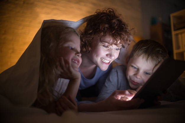 Joven madre leyendo cuentos con dos niños