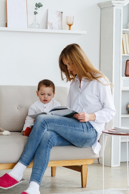 Una joven madre con un lindo hijo leyendo una revista en una luminosa y acogedora sala de estar