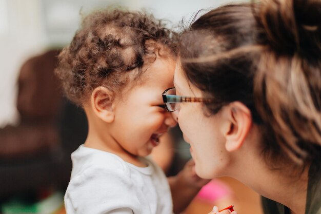 Foto joven madre milenaria y niño pequeño diverso en casa uniéndose