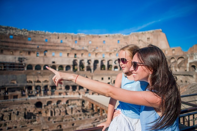 Joven madre y niña abrazando en el Coliseo, Roma, Italia.