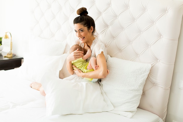 Joven madre y niña linda en la cama