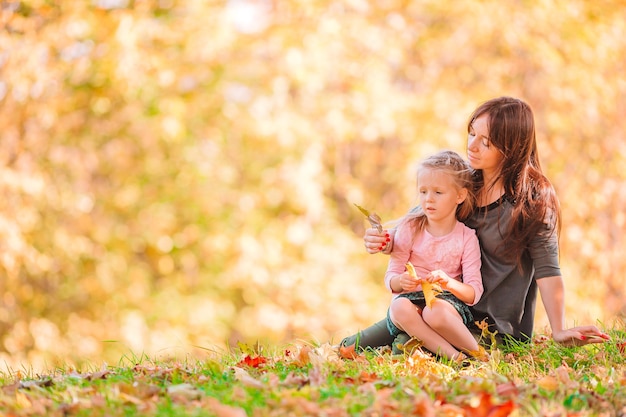 Joven madre y niña en el parque de otoño en octubre