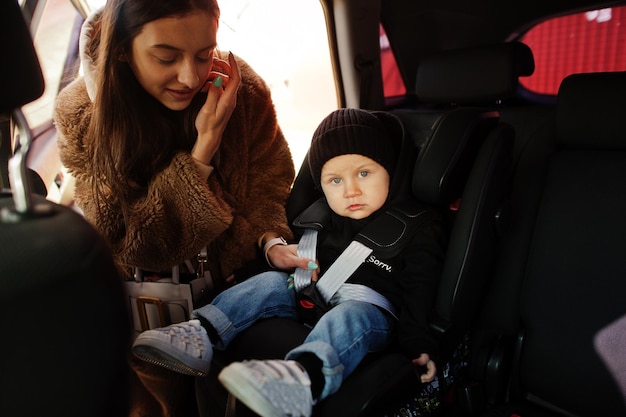 joven, madre, y, niño, en coche, asiento de bebé, en, silla, seguridad, conducción, concepto