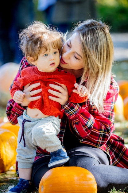 Joven madre con un niño en una ley con calabazas