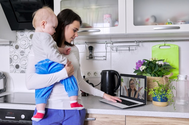 Foto joven madre con un niño en sus brazos hablando en línea con el psicólogo, haciendo videollamadas, videoconferencias usando la computadora portátil en casa. tecnología, salud mental, terapia, concepto de estilo de vida a distancia