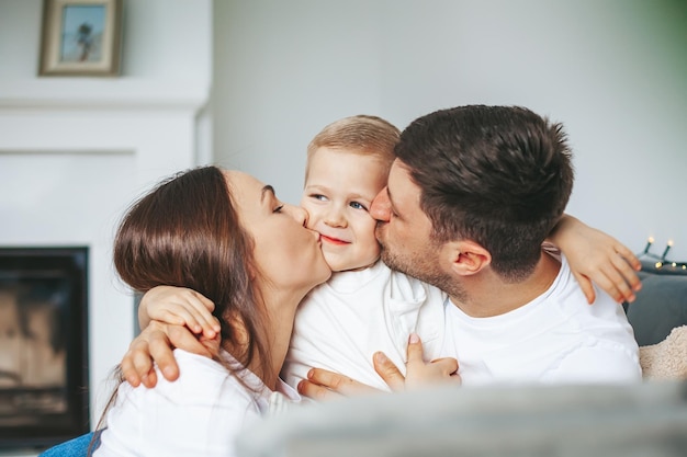 Joven madre y padre besando a su pequeño hijo