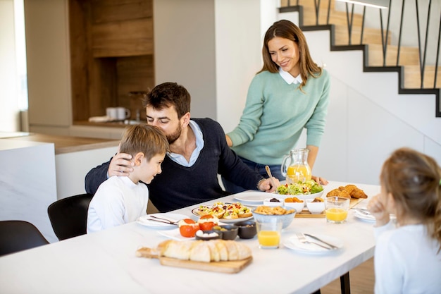 Joven madre preparando el desayuno para su familia en la cocina moderna