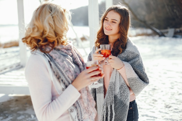 joven madre rubia con su hija adulta en el parque de primavera con mulledwine