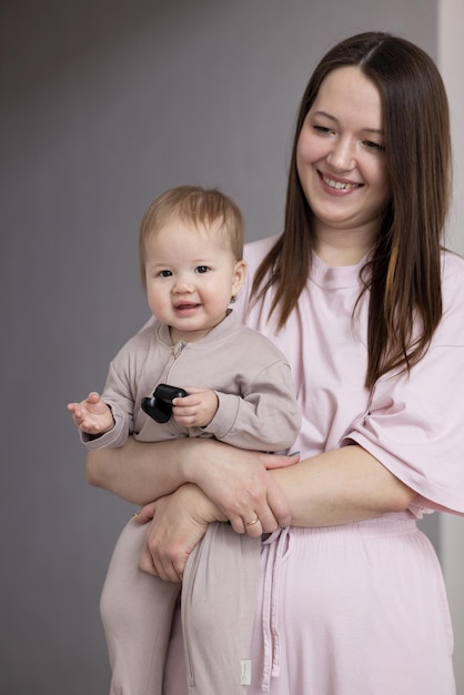 Joven madre sosteniendo a su bebé en sus brazos y sonriendo felizmente