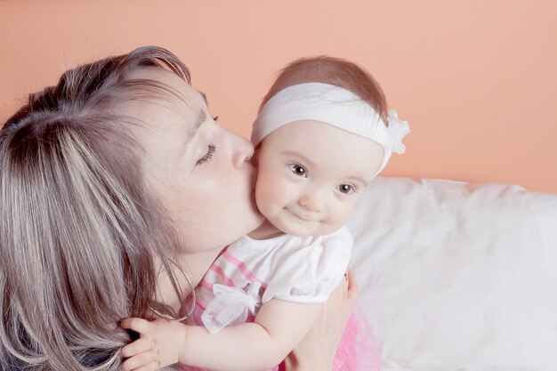 Una joven madre con su bebé lo besa. De cerca.