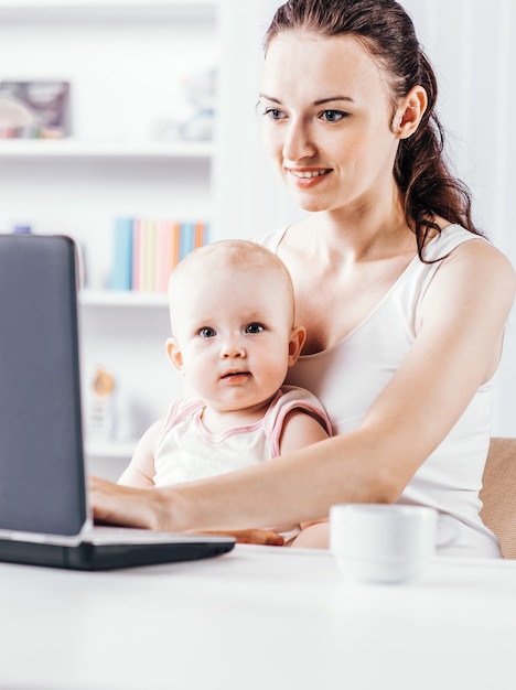 La joven madre y su bebé usando la computadora portátil para comunicarse con la abuela v