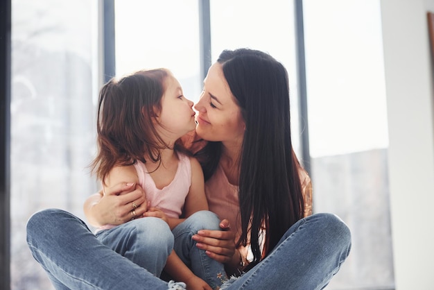 Joven madre con su hija abrazándose en la cama