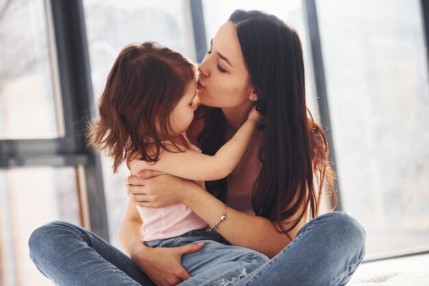 Foto joven madre con su hija abrazándose en la cama