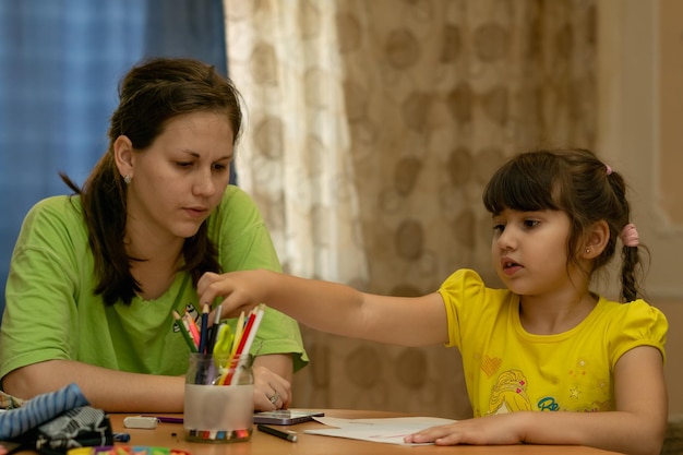 joven madre con su hija ayudándola con la tarea